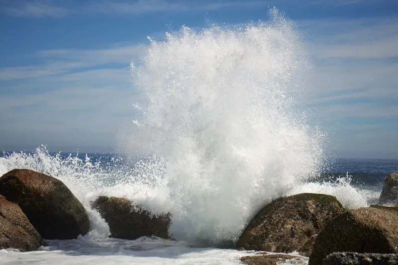 A wave exploding against granite boulders